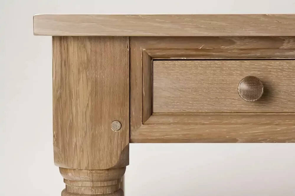 A rectangular wooden refectory table with a drawer at each end and columnar supports with a closeup on the drawers and the wood,  available  to buy on the-salon.com. SALON curates the finest , unique, handmade pieces from the interior industry's best makers and brands. Shop luxury furniture, lighting, rugs, art, antiques and vintage pieces and accessories from SALON interior designed rooms.