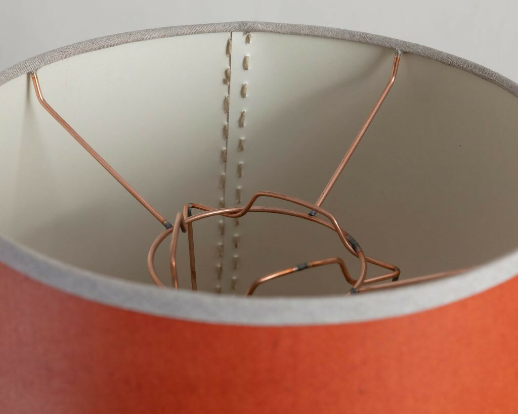 A tapered lampshade with a hand-stitched design, in Pompeian Buff colour, displayed on a stand against a neutral background, available  to buy on the-salon.com. SALON curates the finest , unique, handmade pieces from the interior industry's best makers and brands. Shop luxury furniture, lighting, rugs, art, antiques and vintage pieces and accessories from SALON interior designed rooms.