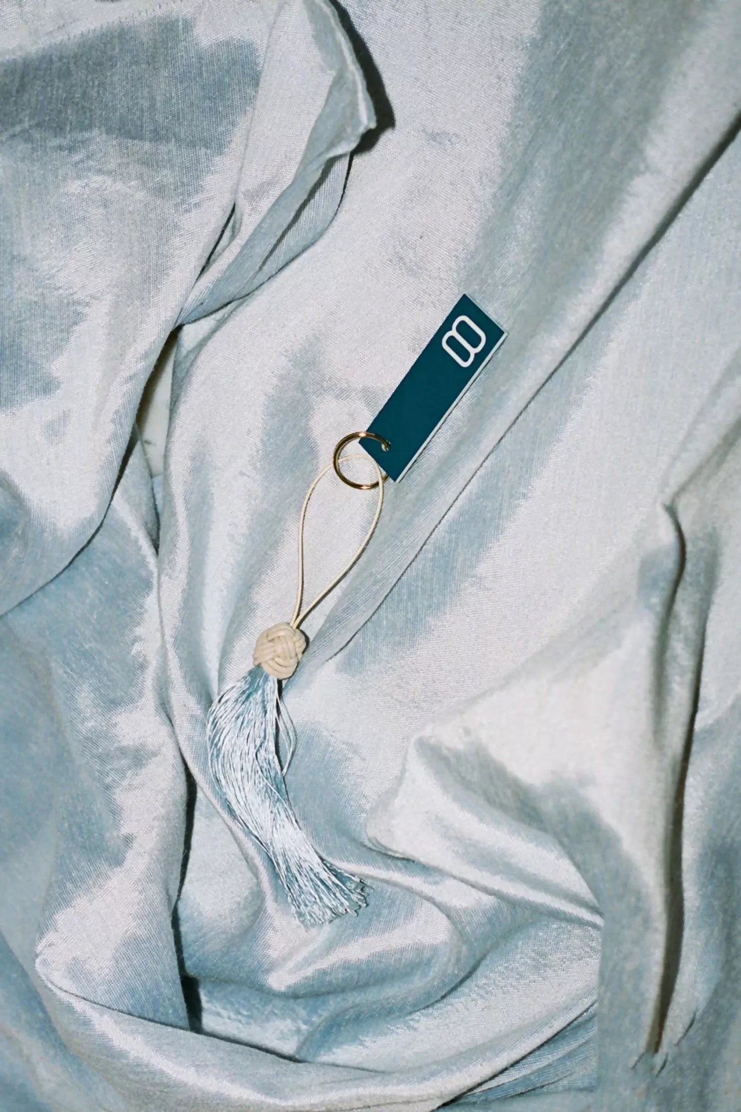 A close-up image of silk sateen fabric in a sky blue colour, displaying its texture and sheen,  available  to buy on the-salon.com. SALON curates the finest , unique, handmade pieces from the interior industry's best makers and brands. Shop luxury furniture, lighting, rugs, art, antiques and vintage pieces and accessories from SALON interior designed rooms.