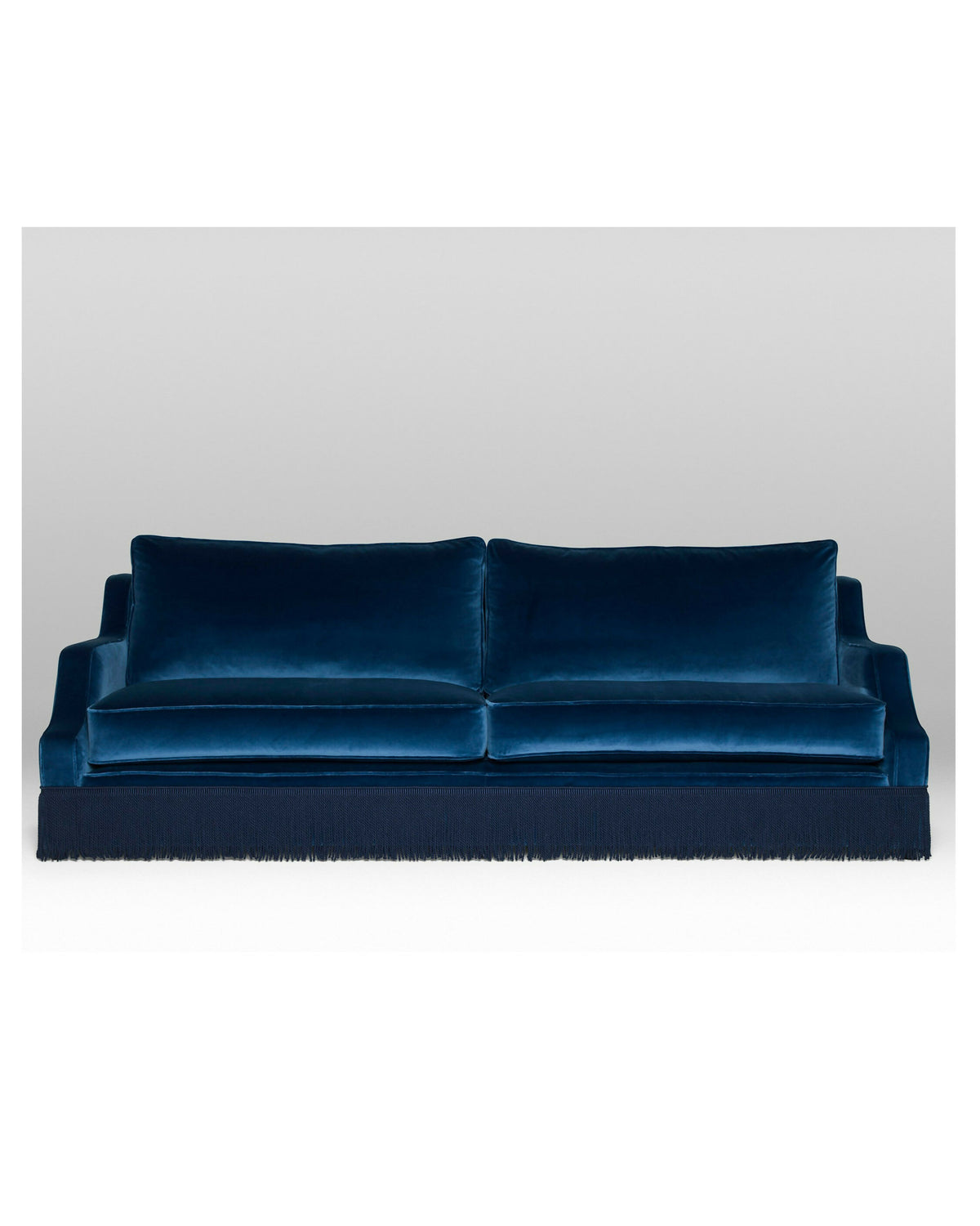 A blue velvet sofa with plush seats and a tasseled fringe, named 'Large Atlanta Sofa by Orior', available  to buy on the-salon.com. SALON curates the finest , unique, handmade pieces from the interior industry's best makers and brands. Shop luxury furniture, lighting, rugs, art, antiques and vintage pieces and accessories from SALON interior designed rooms.