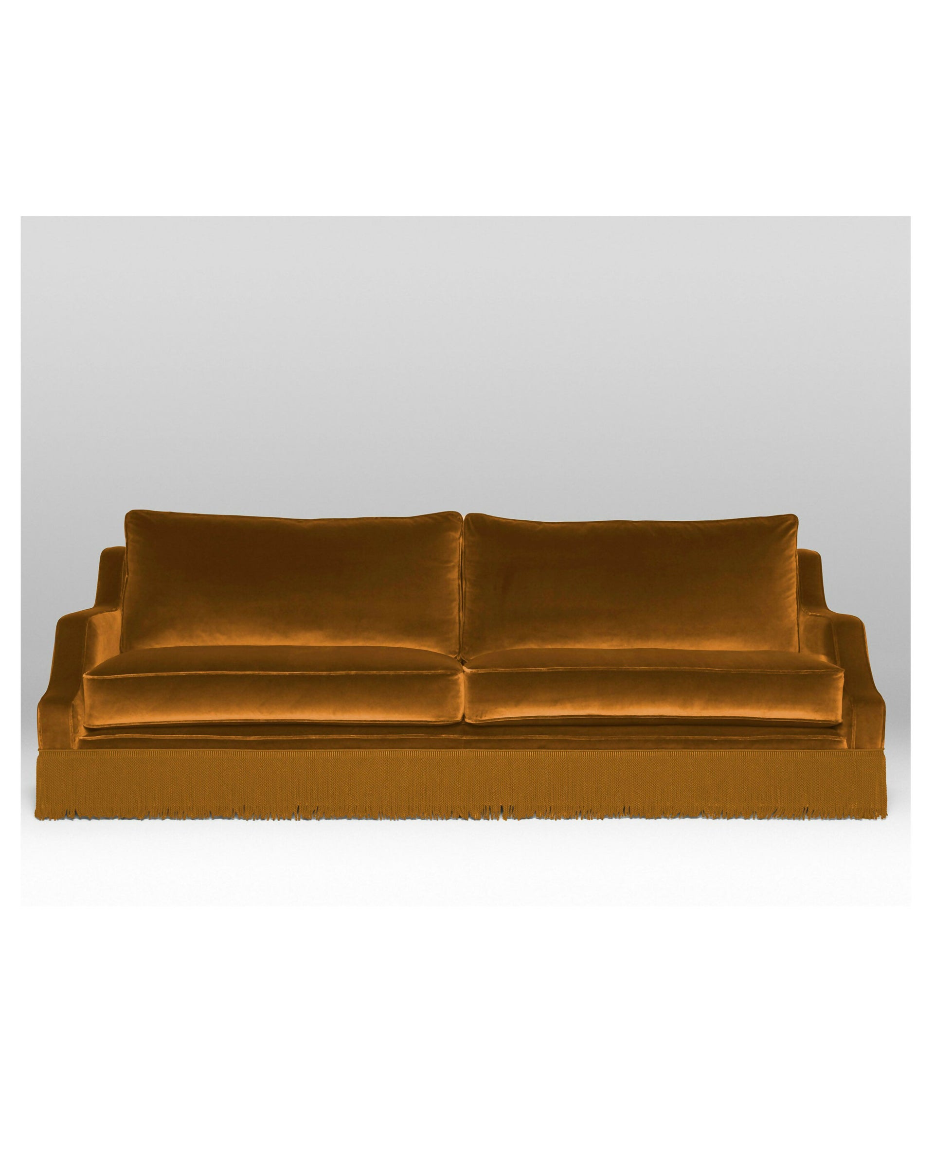 A Mustard velvet sofa with plush seats and a tasseled fringe, named 'Large Atlanta Sofa by Orior', available  to buy on the-salon.com. SALON curates the finest , unique, handmade pieces from the interior industry's best makers and brands. Shop luxury furniture, lighting, rugs, art, antiques and vintage pieces and accessories from SALON interior designed rooms.