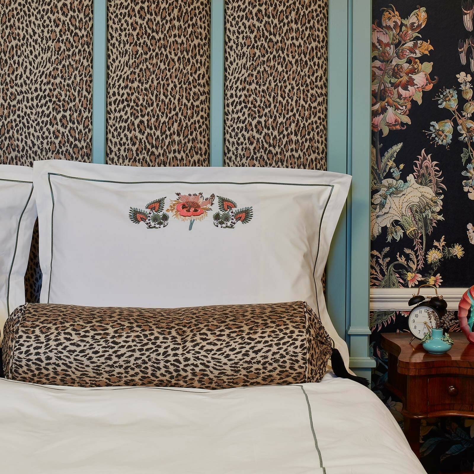 Bedroom with leopard print pillows and wallpaper, and a floral-patterned nightstand,  available  to buy on the-salon.com. SALON curates the finest , unique, handmade pieces from the interior industry's best makers and brands. Shop luxury furniture, lighting, rugs, art, antiques and vintage pieces and accessories from SALON interior designed rooms.