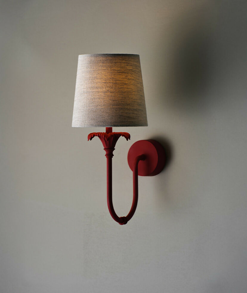 A wall-mounted light fixture with a red-colored metal arm and a white, solid-patterned lampshade,  available  to buy on the-salon.com. SALON curates the finest , unique, handmade pieces from the interior industry's best makers and brands. Shop luxury furniture, lighting, rugs, art, antiques and vintage pieces and accessories from SALON interior designed rooms.