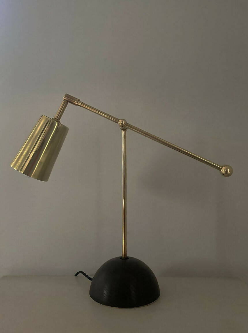 An elegant brass desk lamp with a hand turned solid oak base and a hand polished brass finish, positioned against a neutral background,  available  to buy on the-salon.com. SALON curates the finest , unique, handmade pieces from the interior industry's best makers and brands. Shop luxury furniture, lighting, rugs, art, antiques and vintage pieces and accessories from SALON interior designed rooms.