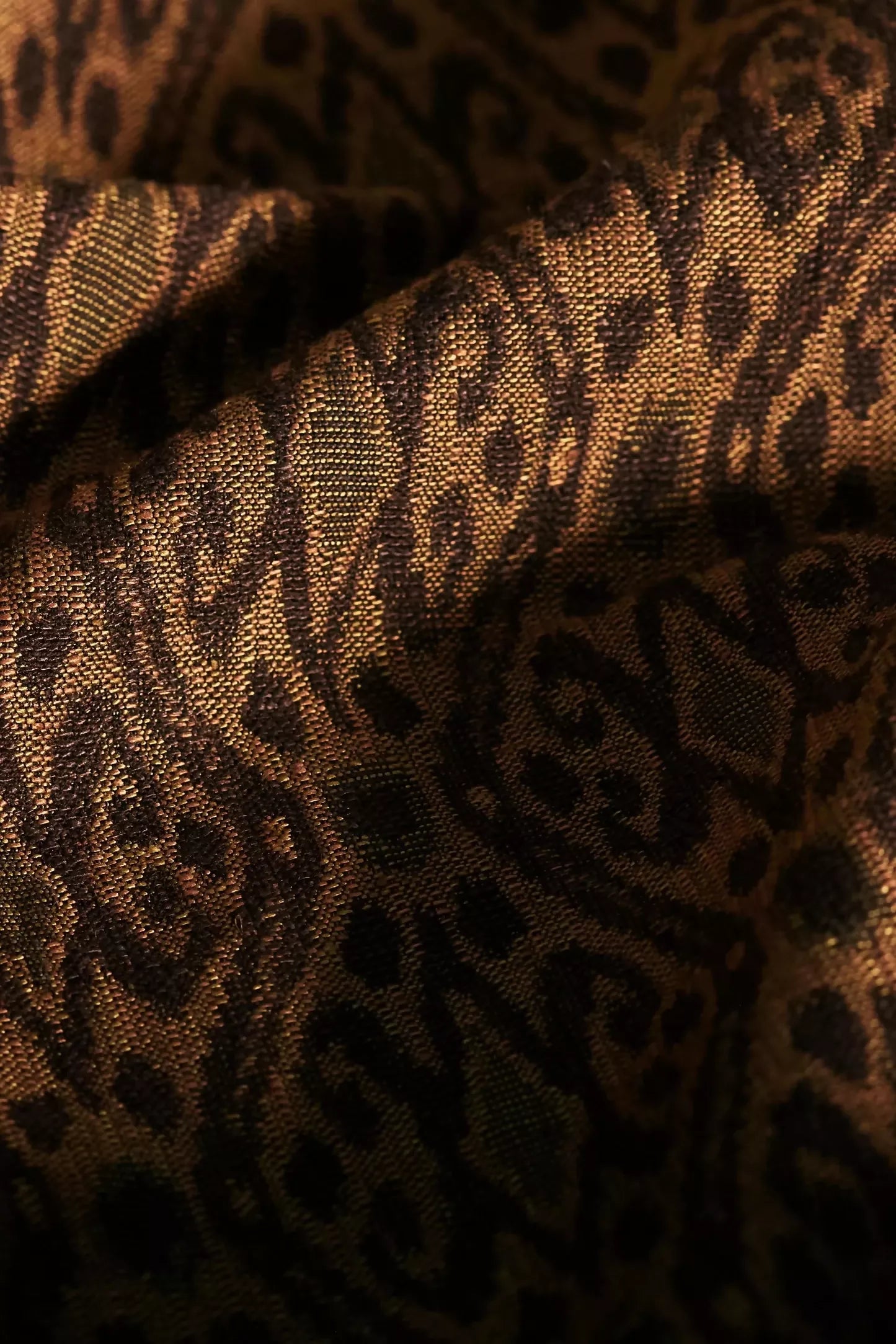 Close-up of a woven ikat fabric in shades of brown, with a geometric pattern featuring Tiger's Eye stone-like iridescence,  available  to buy on the-salon.com. SALON curates the finest , unique, handmade pieces from the interior industry's best makers and brands. Shop luxury furniture, lighting, rugs, art, antiques and vintage pieces and accessories from SALON interior designed rooms.
