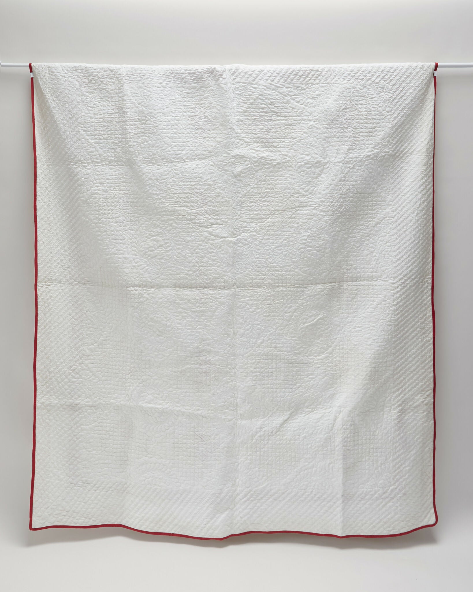 White quilt with red border on a white background,  available  to buy on the-salon.com. SALON curates the finest , unique, handmade pieces from the interior industry's best makers and brands. Shop luxury furniture, lighting, rugs, art, antiques and vintage pieces and accessories from SALON interior designed rooms.