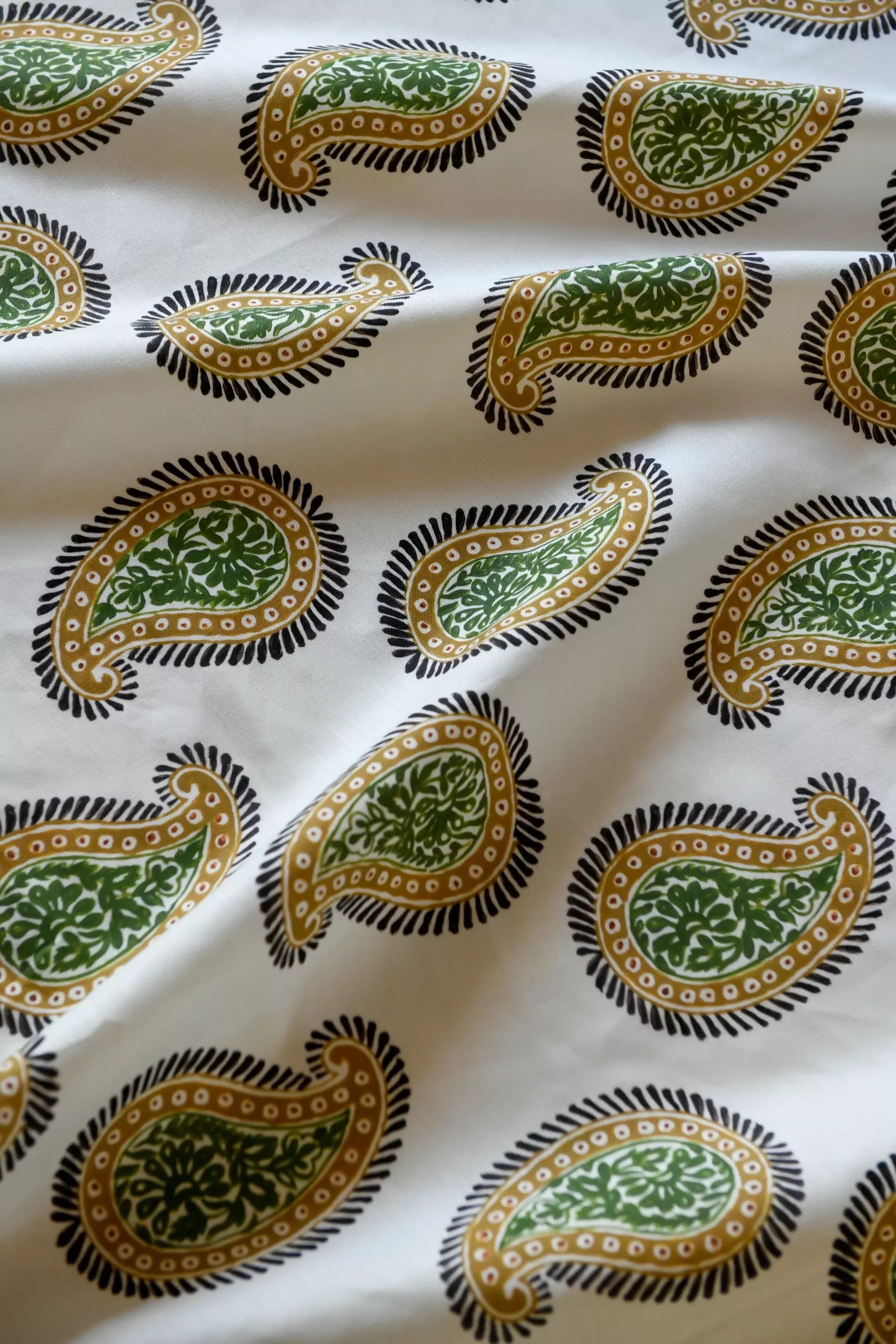 Close-up of a paisley patterned fabric with a design consisting of teardrop shapes and floral elements, predominantly in dark colors on a light background,available  to buy on the-salon.com. SALON curates the finest , unique, handmade pieces from the interior industry's best makers and brands. Shop luxury furniture, lighting, rugs, art, antiques and vintage pieces and accessories from SALON interior designed rooms