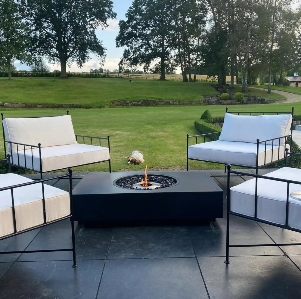 Outdoor patio setup with fire pit and cushioned chairs in a garden setting