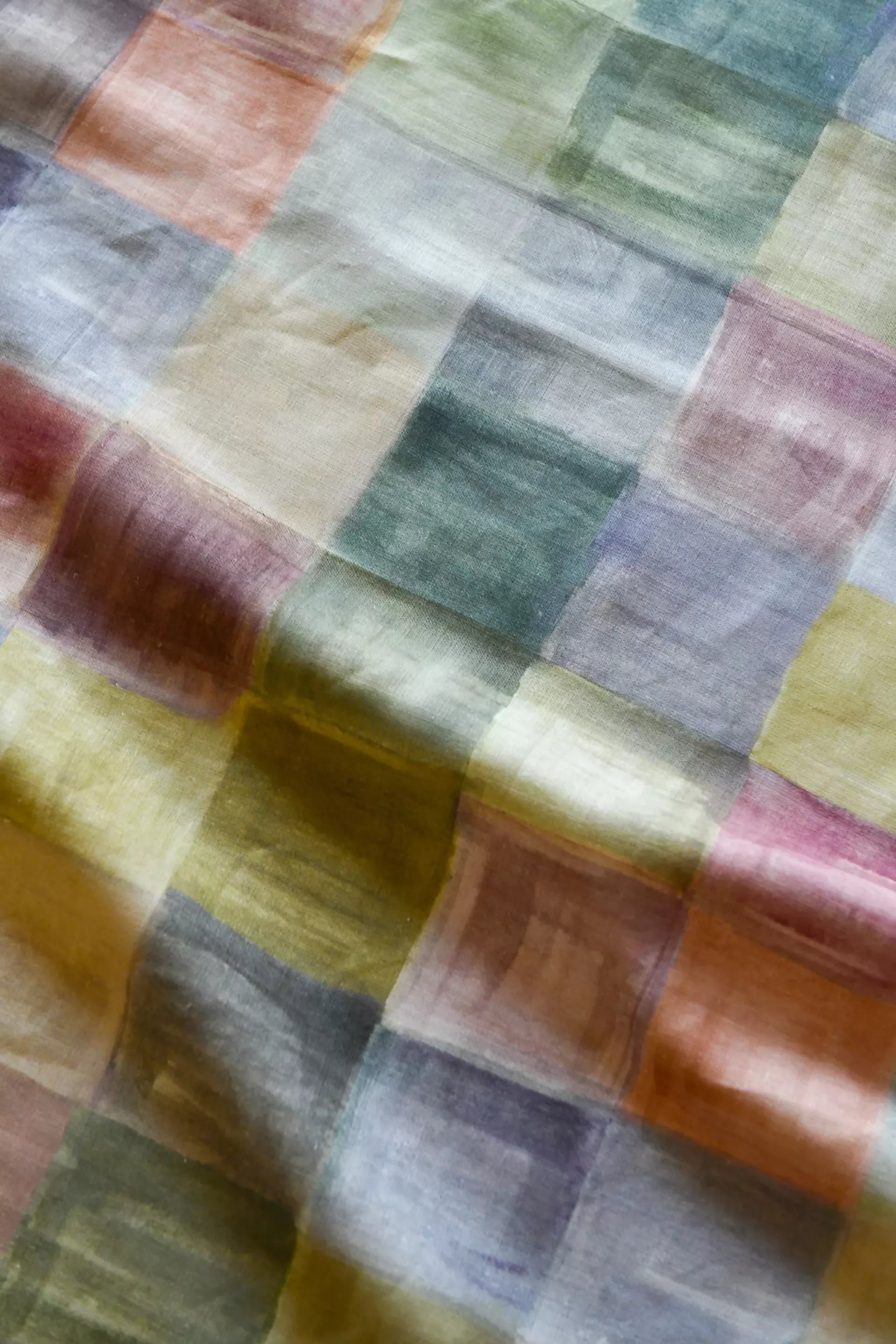 A close-up of a plaid fabric featuring a pattern of various solid colors, including blue, pink, green, and yellow,  available  to buy on the-salon.com. SALON curates the finest , unique, handmade pieces from the interior industry's best makers and brands. Shop luxury furniture, lighting, rugs, art, antiques and vintage pieces and accessories from SALON interior designed rooms.