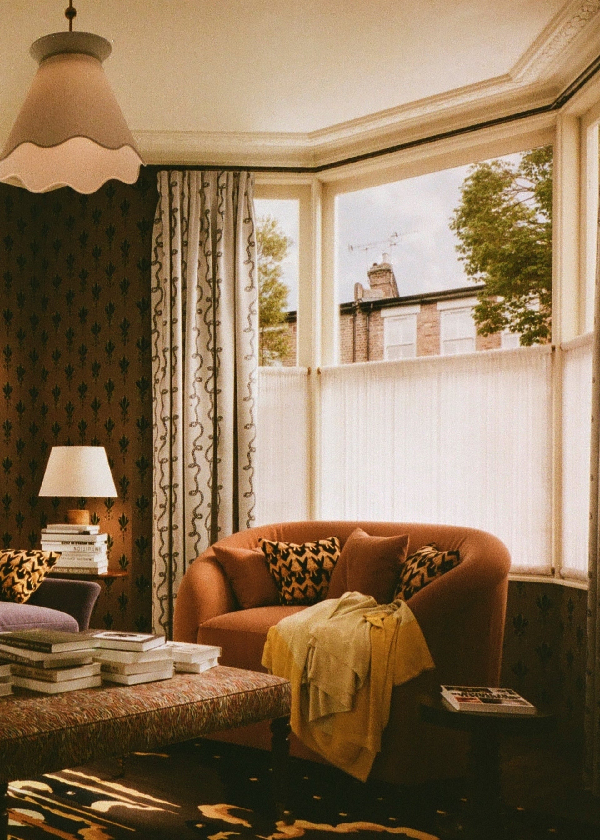 Cozy living room with a brown sofa, coffee table, and large window. SALON curates the finest unique handmade pieces from the interior industry's best makers and brands. Shop luxury furniture, lighting, rugs, art, antiques and vintage pieces and accessories from SALON interior designed rooms. 
