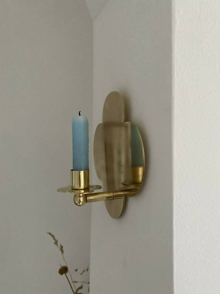 A solid brass wall-mounted candle sconce in the shape of a quatrefoil with  candle,  available  to buy on the-salon.com. SALON curates the finest , unique, handmade pieces from the interior industry's best makers and brands. Shop luxury furniture, lighting, rugs, art, antiques and vintage pieces and accessories from SALON interior designed rooms.