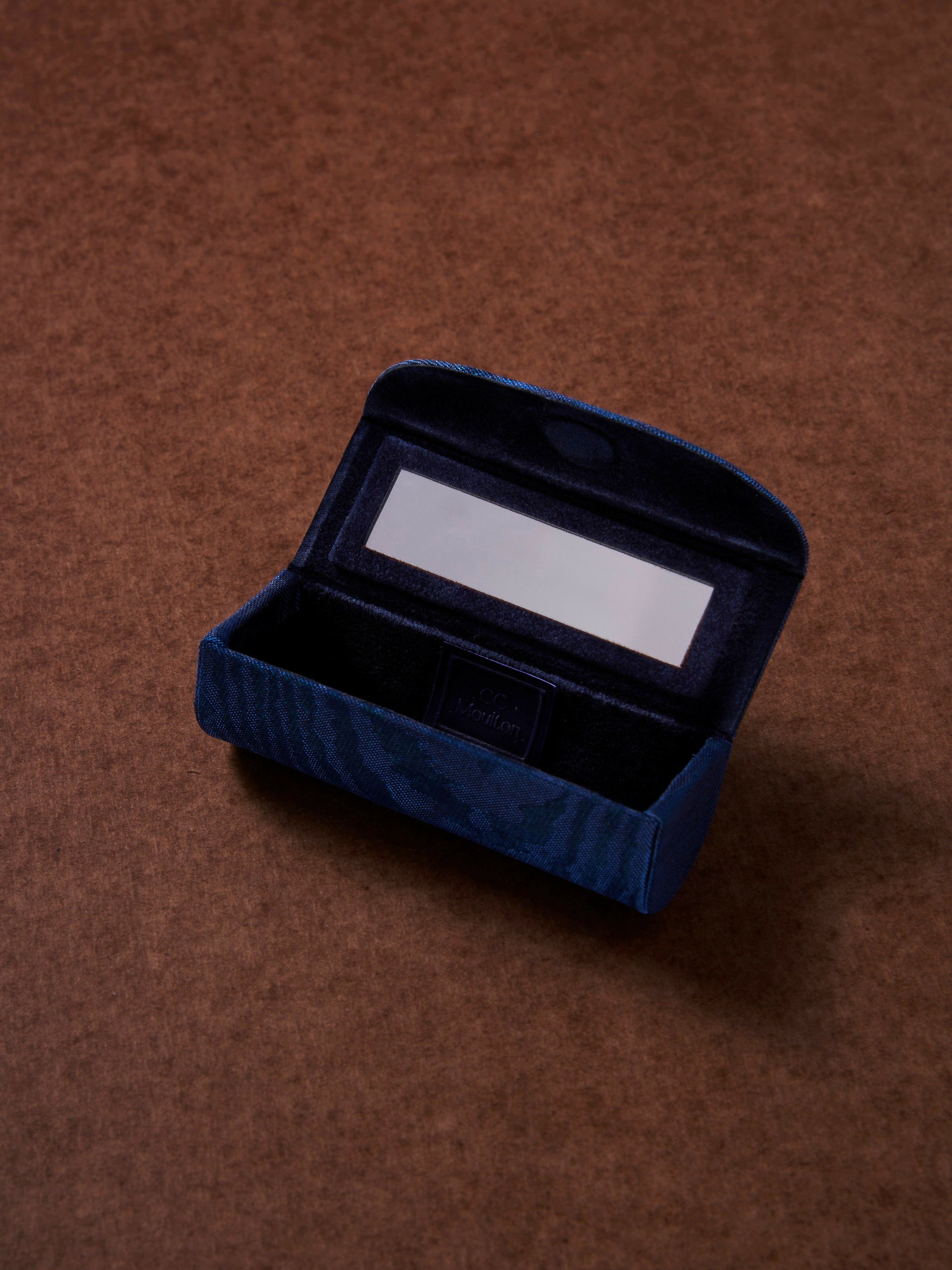 Blue velvet jewelry box with a white card on a brown background,  available  to buy on the-salon.com. SALON curates the finest , unique, handmade pieces from the interior industry's best makers and brands. Shop luxury furniture, lighting, rugs, art, antiques and vintage pieces and accessories from SALON interior designed rooms.