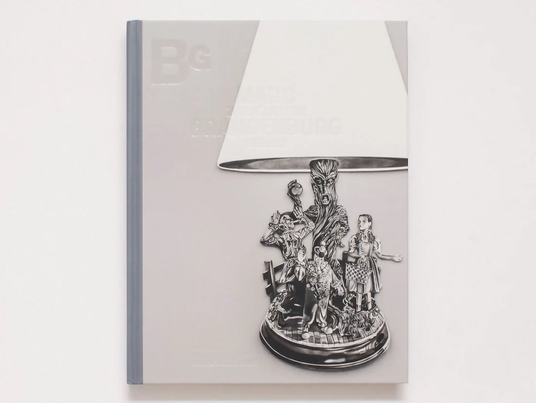 A square decorative lampshade with a highly detailed, metallic silver fairy tale character sculpture on its base, set against a light gray background.