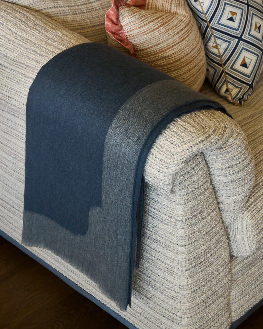 A folded slate blue cashmere throw blanket with a decorative border detail,  available  to buy on the-salon.com. SALON curates the finest , unique, handmade pieces from the interior industry's best makers and brands. Shop luxury furniture, lighting, rugs, art, antiques and vintage pieces and accessories from SALON interior designed rooms.