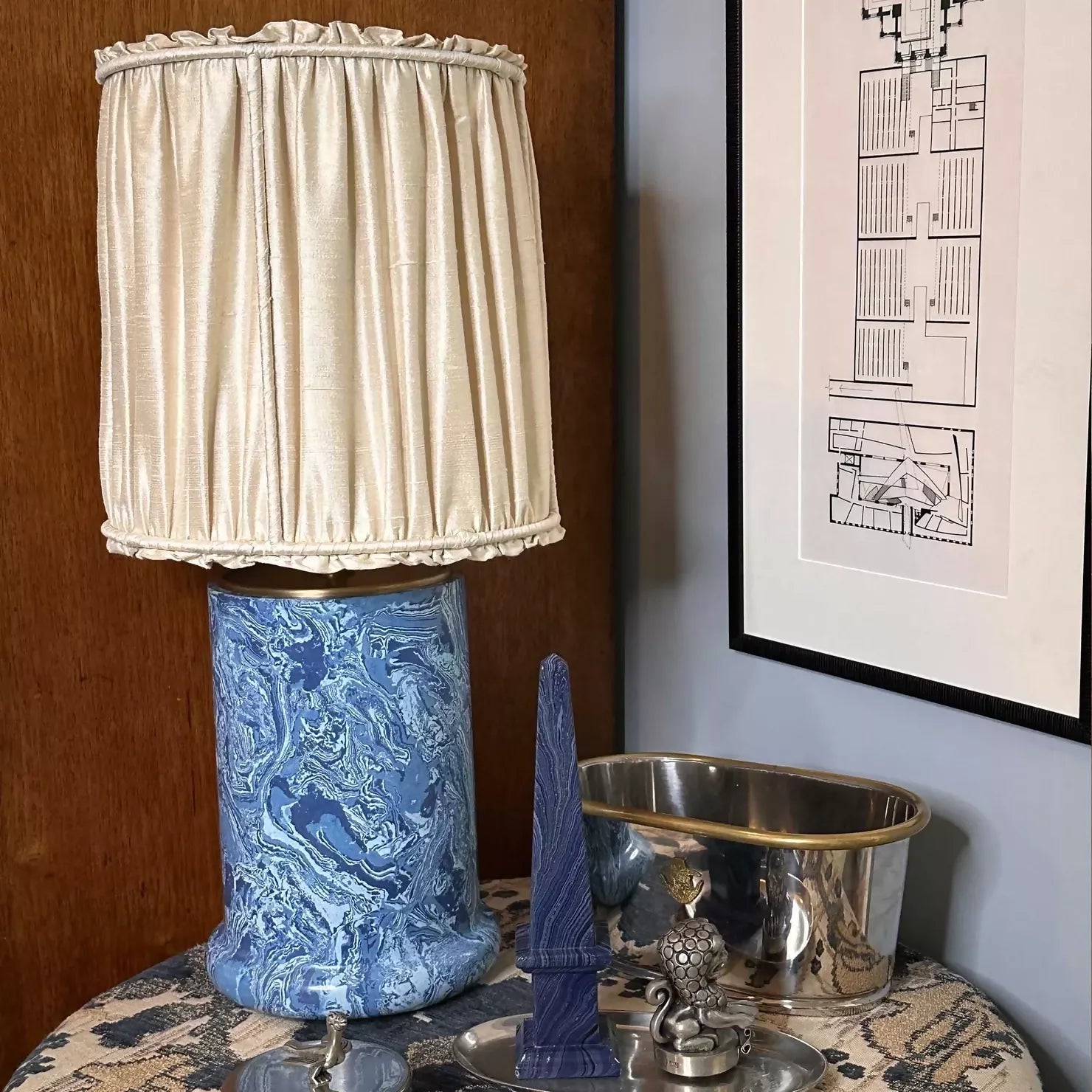 A blue marbled base table lamp with brass detailing, topped with a gold pleated shade,  available  to buy on the-salon.com. SALON curates the finest , unique, handmade pieces from the interior industry's best makers and brands. Shop luxury furniture, lighting, rugs, art, antiques and vintage pieces and accessories from SALON interior designed rooms.