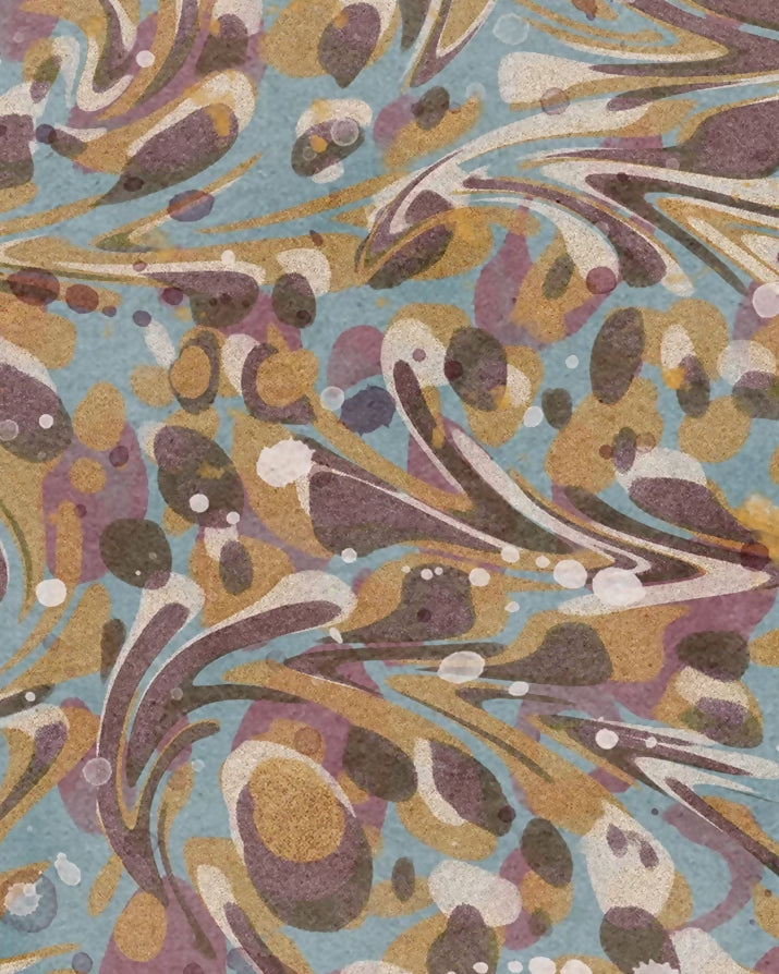 A square fabric swatch with scalloped edges featuring an abstract marbled pattern in muted blue, tan, brown, purple, and cream.