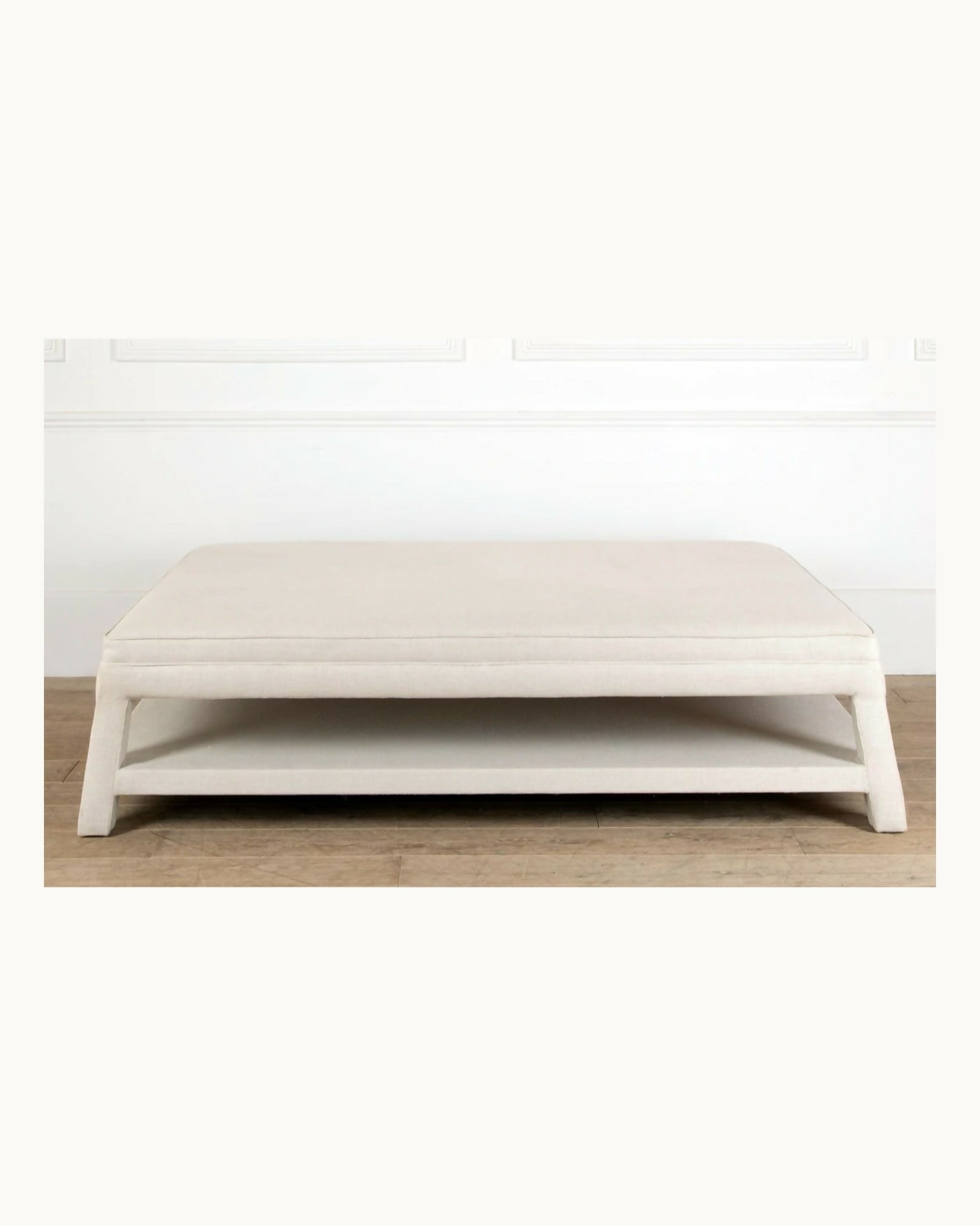 White ottoman on a wooden floor with a white wall background,  available  to buy on the-salon.com. SALON curates the finest , unique, handmade pieces from the interior industry's best makers and brands. Shop luxury furniture, lighting, rugs, art, antiques and vintage pieces and accessories from SALON interior designed rooms.