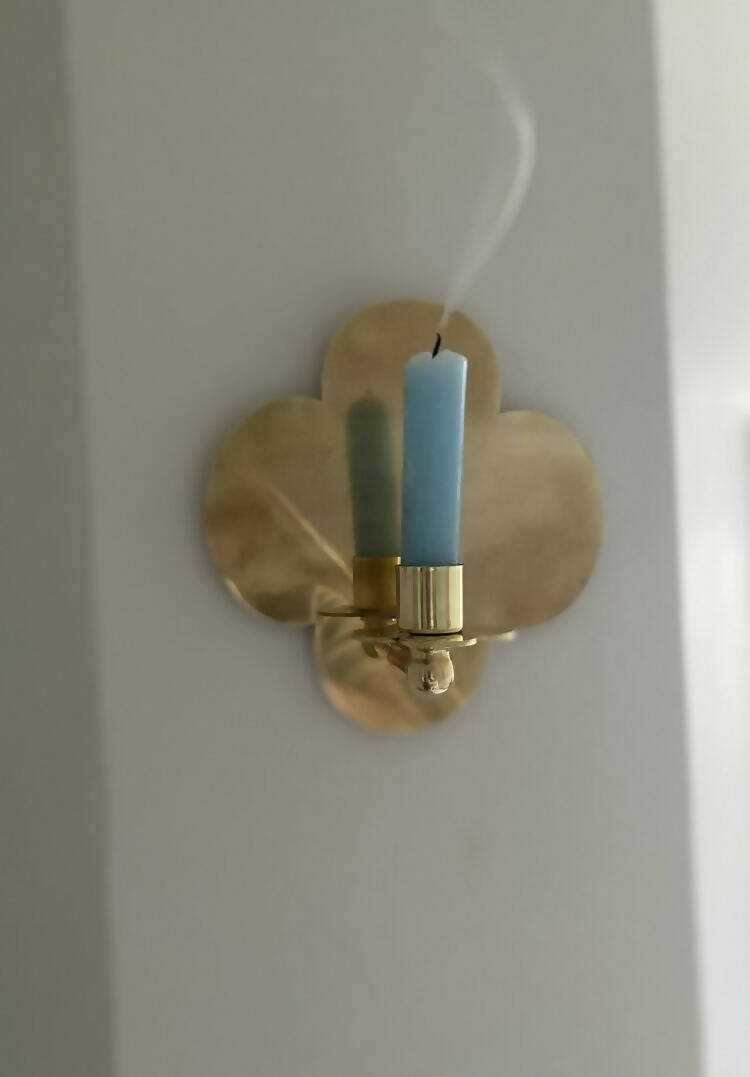 A solid brass wall-mounted candle sconce in the shape of a quatrefoil with a candle,  available  to buy on the-salon.com. SALON curates the finest , unique, handmade pieces from the interior industry's best makers and brands. Shop luxury furniture, lighting, rugs, art, antiques and vintage pieces and accessories from SALON interior designed rooms.