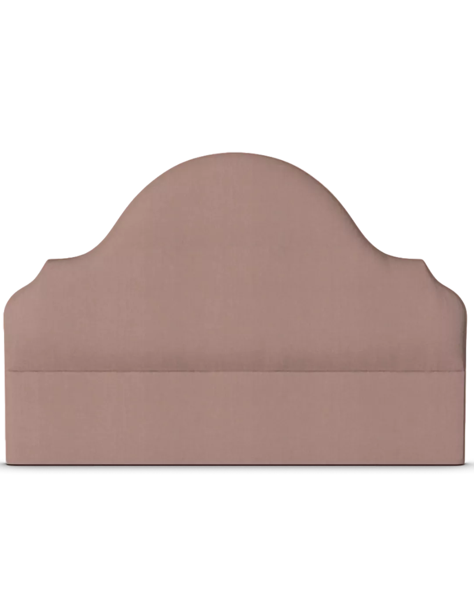 A dusty rose upholstered headboard with a gently curved, scalloped top edge, shown against a plain white background.