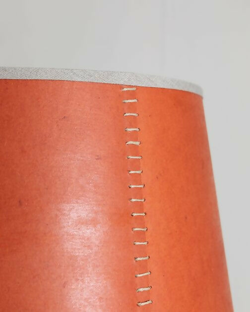 A tapered lampshade with a hand-stitched design, in Pompeian Buff colour, displayed on a stand against a neutral background, available  to buy on the-salon.com. SALON curates the finest , unique, handmade pieces from the interior industry's best makers and brands. Shop luxury furniture, lighting, rugs, art, antiques and vintage pieces and accessories from SALON interior designed rooms.