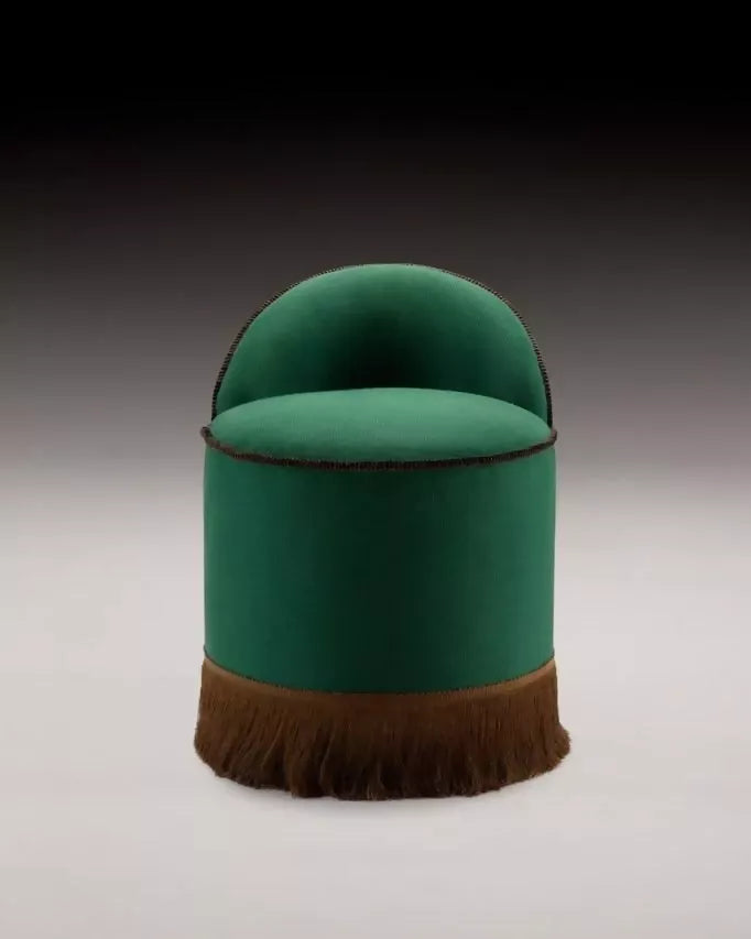 A green upholstered Inferi stool with a curvilinear backrest and a brown fringe at the base, designed for room service or salon use,  available  to buy on the-salon.com. SALON curates the finest , unique, handmade pieces from the interior industry's best makers and brands. Shop luxury furniture, lighting, rugs, art, antiques and vintage pieces and accessories from SALON interior designed rooms.