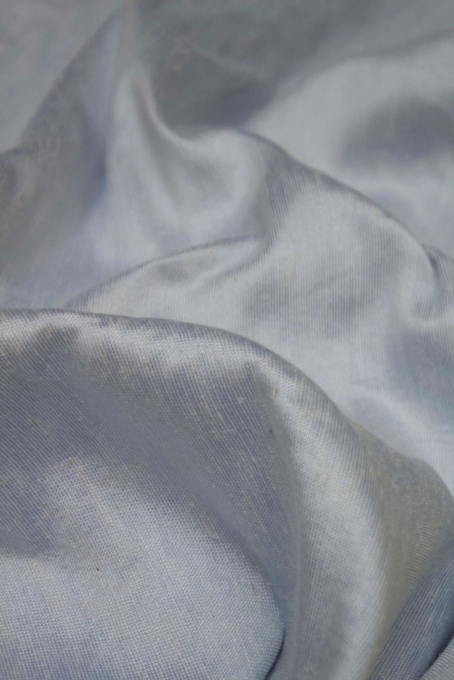 A close-up image of silk sateen fabric in a sky blue colour, displaying its texture and sheen,  available  to buy on the-salon.com. SALON curates the finest , unique, handmade pieces from the interior industry's best makers and brands. Shop luxury furniture, lighting, rugs, art, antiques and vintage pieces and accessories from SALON interior designed rooms.