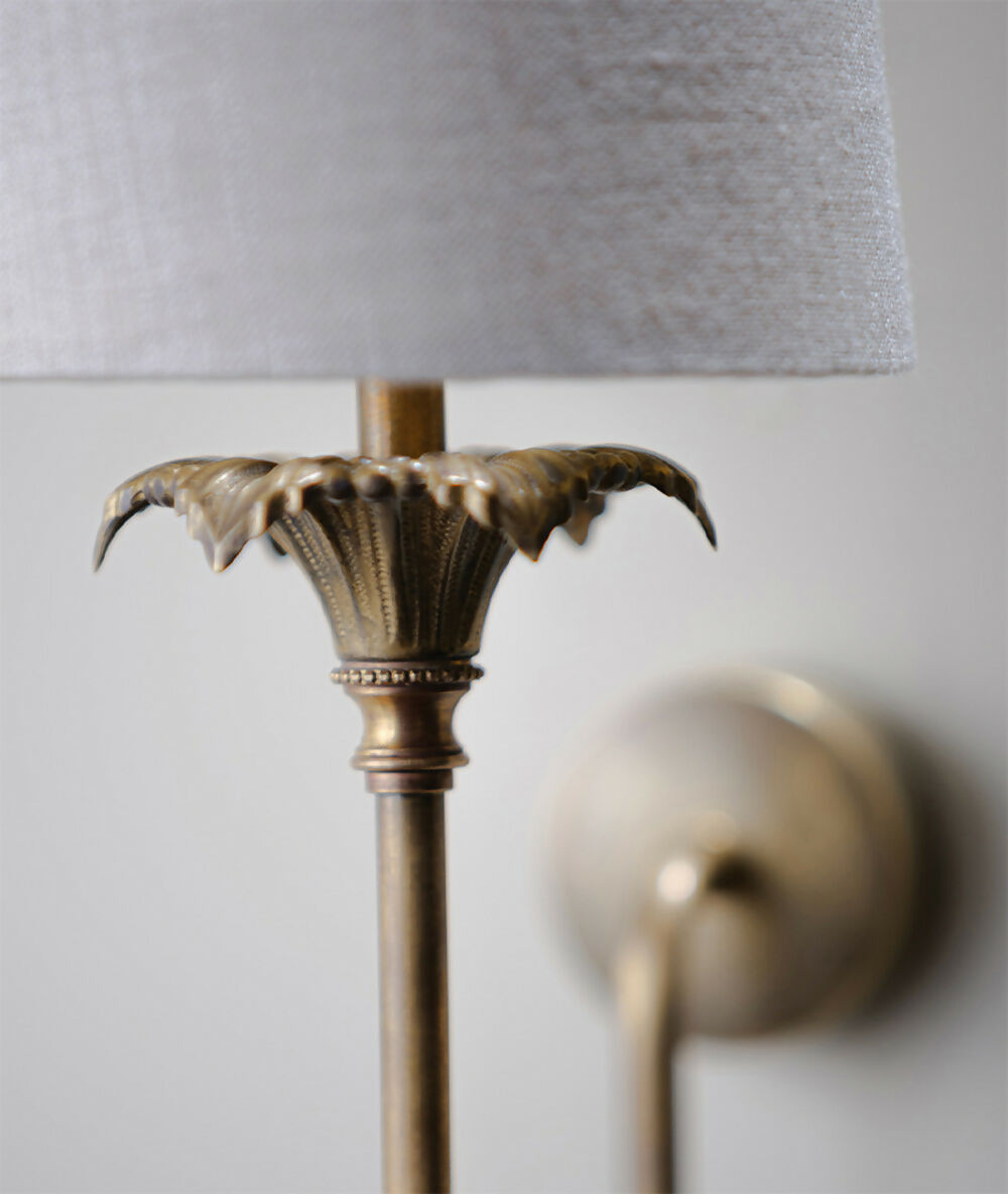 Close-up of a decorative wall lamp with a gray shade,  available  to buy on the-salon.com. SALON curates the finest , unique, handmade pieces from the interior industry's best makers and brands. Shop luxury furniture, lighting, rugs, art, antiques and vintage pieces and accessories from SALON interior designed rooms.