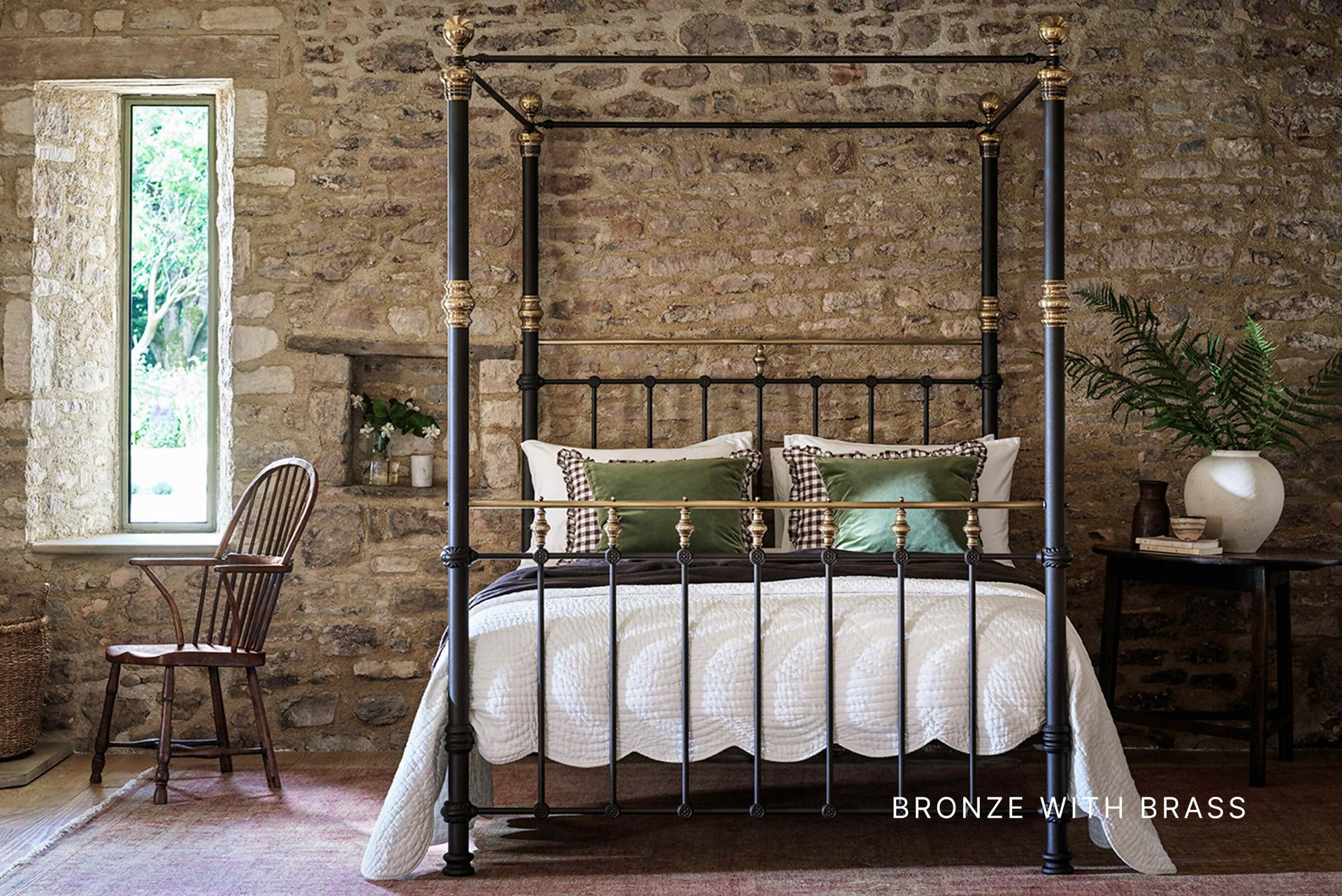 Bronze and brass four-poster bed in a rustic bedroom with stone walls and a window,available to buy from the-salon.com. SALON curates the finest unique handmade pieces from the interior industry's best makers and brands. Shop luxury furniture, lighting, rugs, art, antiques and vintage pieces and accessories from SALON interior designed rooms. 