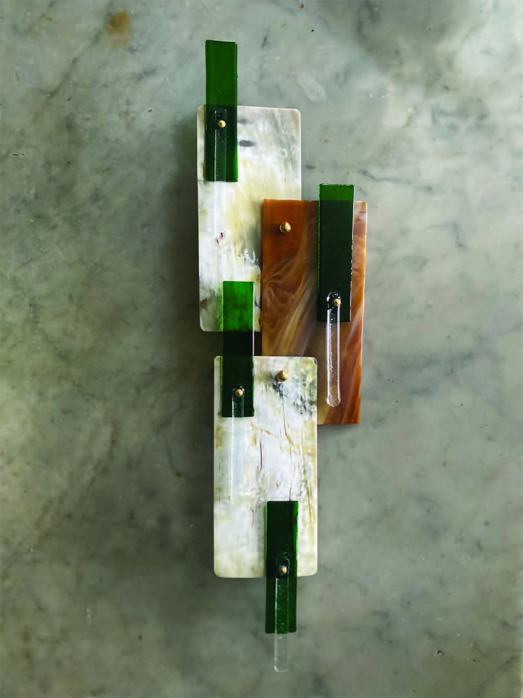 Decorative wall sconce with green and brown accents on a textured wall.