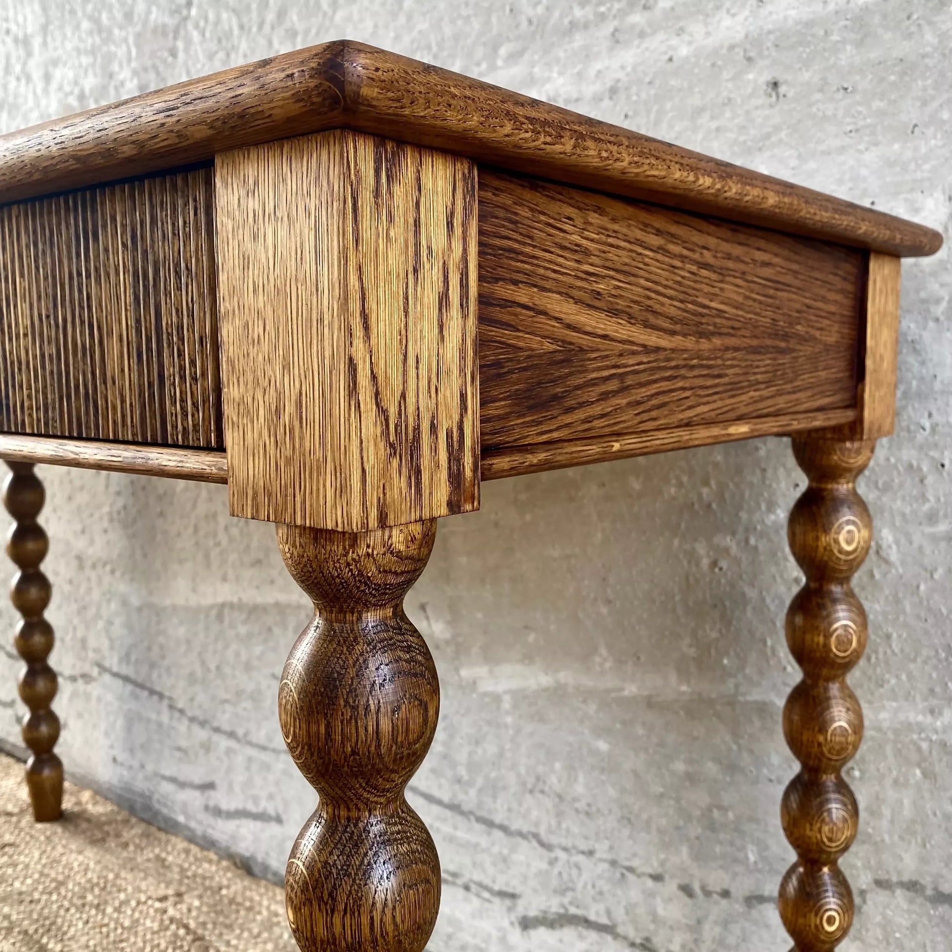 Wooden side table with turned legs against a textured wall, available to buy from the-salon.com. SALON curates the finest unique handmade pieces from the interior industry's best makers and brands. Shop luxury furniture, lighting, rugs, art, antiques and vintage pieces and accessories from SALON interior designed rooms. 