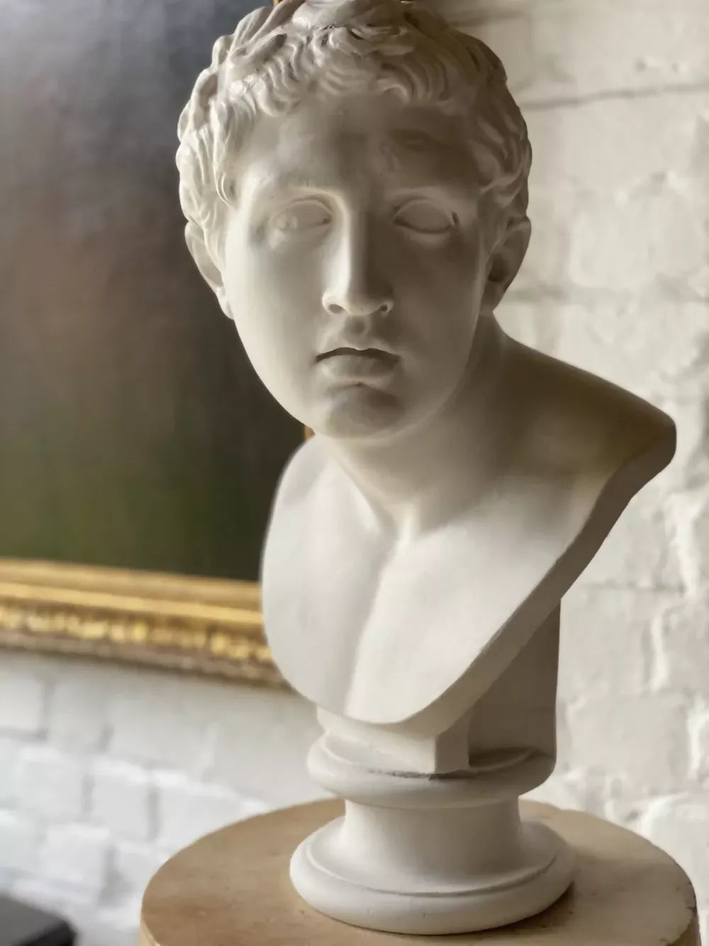 White marble bust on a pedestal with decorative wall in the background available to buy from the-salon.com. SALON curates the finest unique handmade pieces from the interior industry's best makers and brands. Shop luxury furniture, lighting, rugs, art, antiques and vintage pieces and accessories from SALON interior designed rooms.