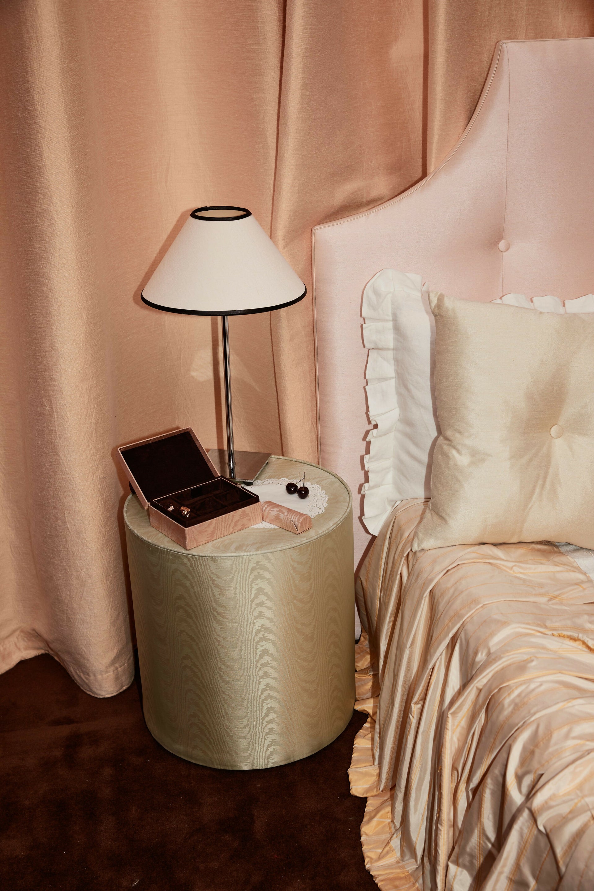 Small round table with a lamp and jewelry box next to a bed with pink bedding,  available  to buy on the-salon.com. SALON curates the finest , unique, handmade pieces from the interior industry's best makers and brands. Shop luxury furniture, lighting, rugs, art, antiques and vintage pieces and accessories from SALON interior designed rooms.