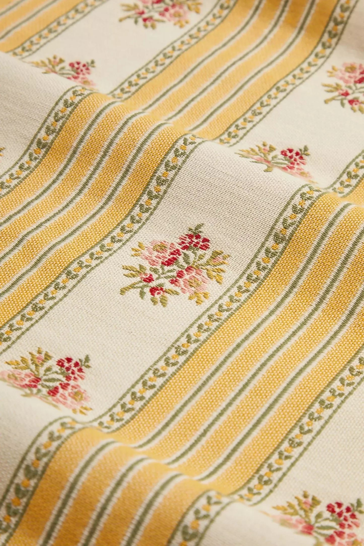 Close-up view of a jacquard weave fabric featuring a sofa stripe pattern with yellow and green stripes and embroidered floral motifs,  available  to buy on the-salon.com. SALON curates the finest , unique, handmade pieces from the interior industry's best makers and brands. Shop luxury furniture, lighting, rugs, art, antiques and vintage pieces and accessories from SALON interior designed rooms.