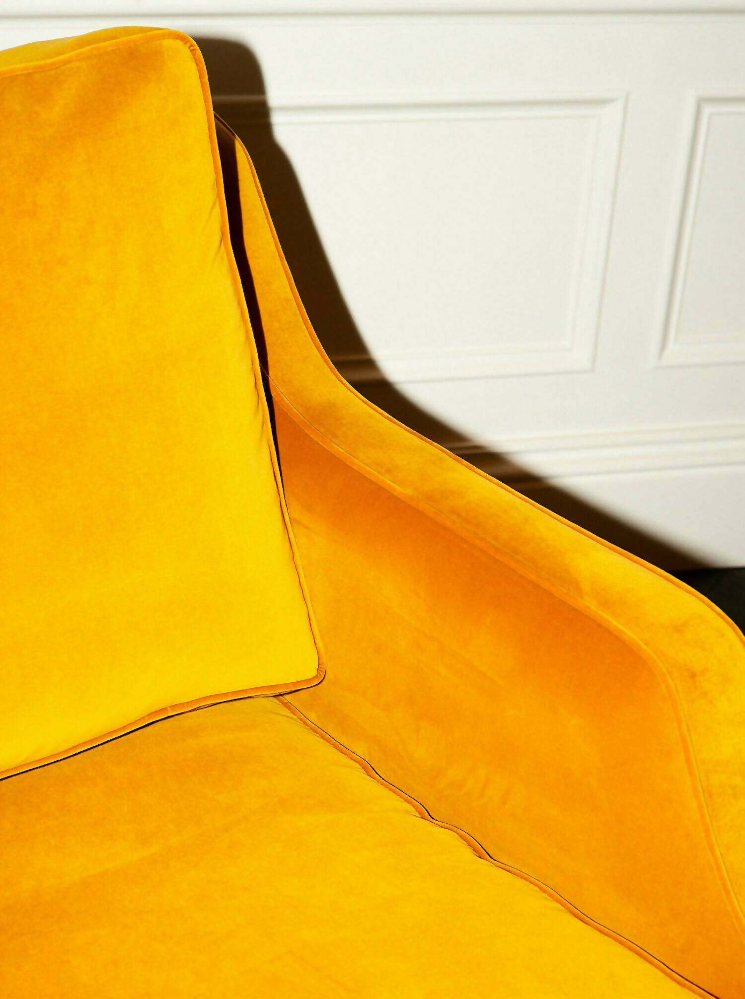 A yellow velvet sofa with plush seats and a tasseled fringe, named 'Large Atlanta Sofa by Orior', available  to buy on the-salon.com. SALON curates the finest , unique, handmade pieces from the interior industry's best makers and brands. Shop luxury furniture, lighting, rugs, art, antiques and vintage pieces and accessories from SALON interior designed rooms.
